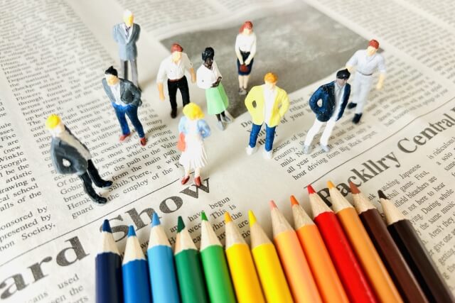 新聞上のカラー鉛筆と小さな人形